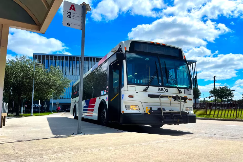 Houston Metro bus at a bus stop with bright blur cloudy sky in background